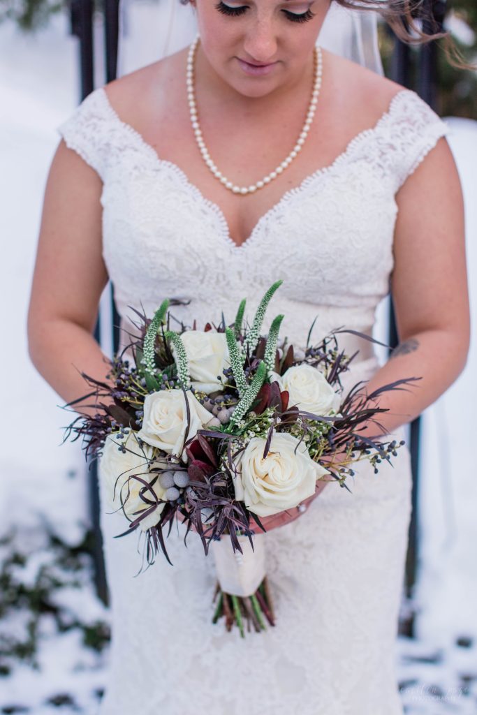 Winter bride holding wedding bouquet with reds and greens
