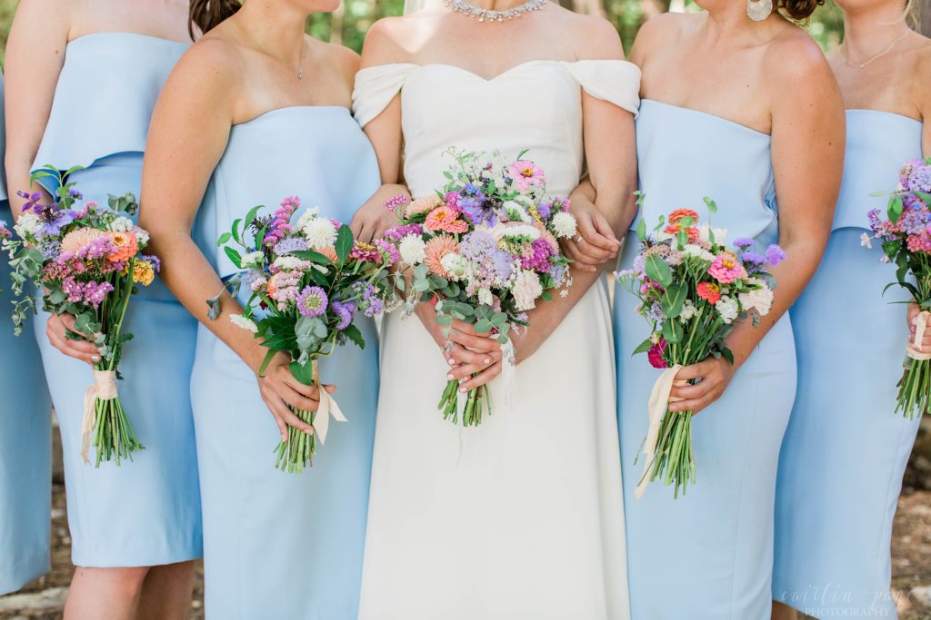 Bride and bridesmaids holding bouquets full of mismatched wildflowers