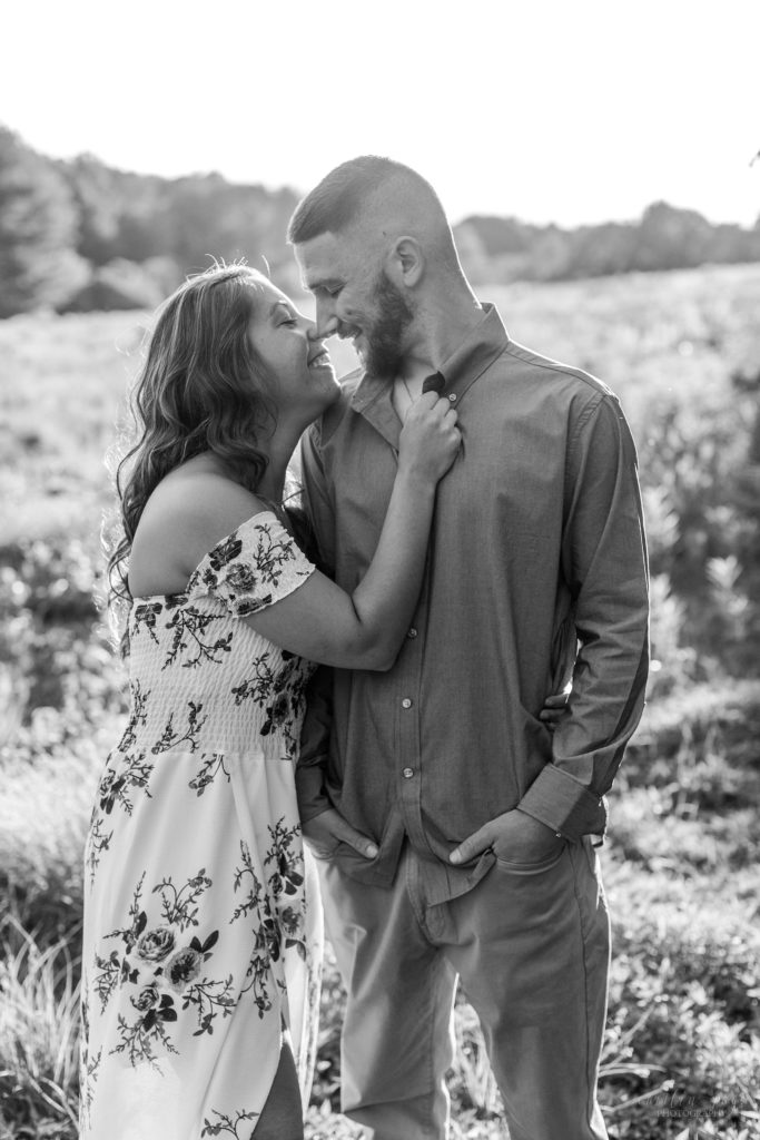 Black and white photo of man and woman almost kissing in a field
