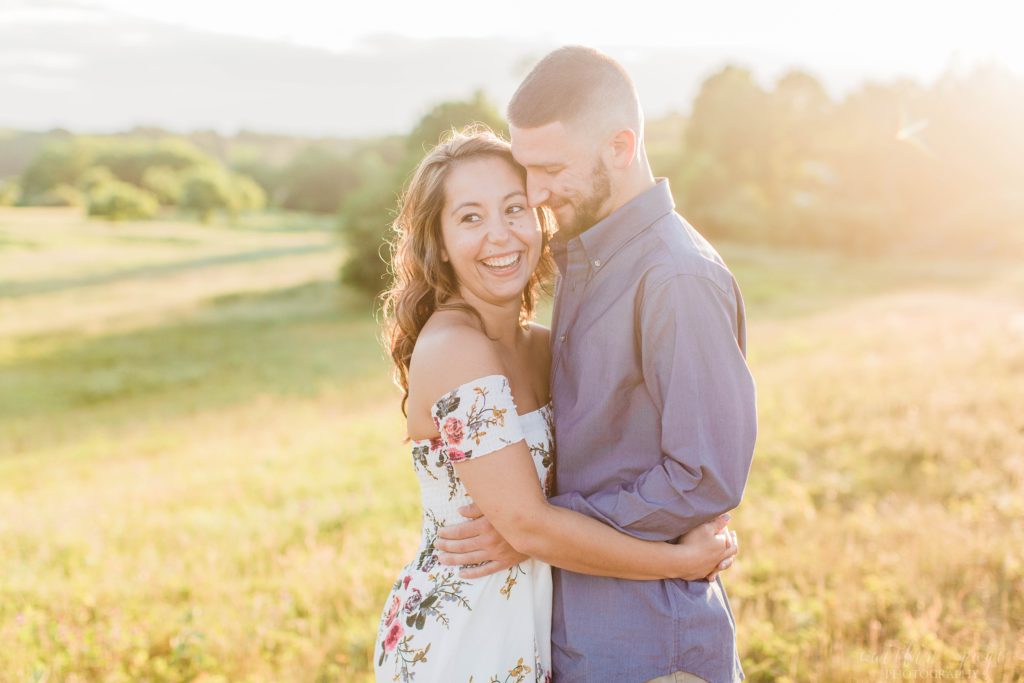 Man nuzzling woman in a field at sunset