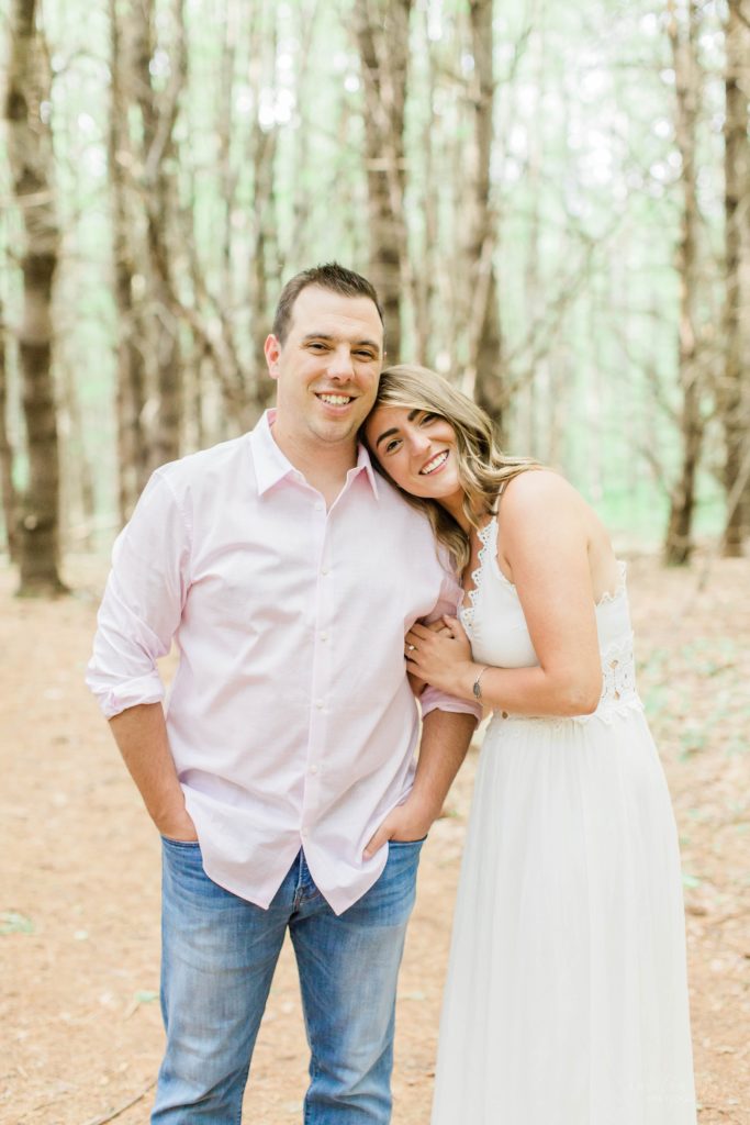 Woman laying her head on man's shoulder in the woods