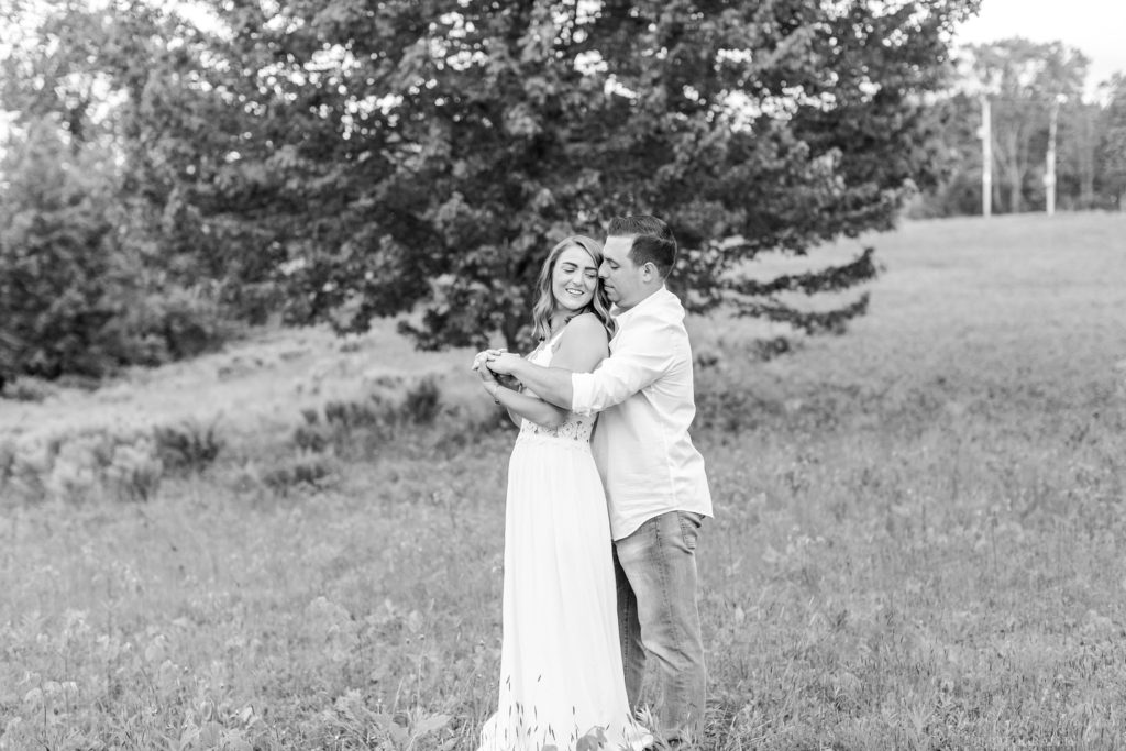 Black and white photo of man holding woman in field