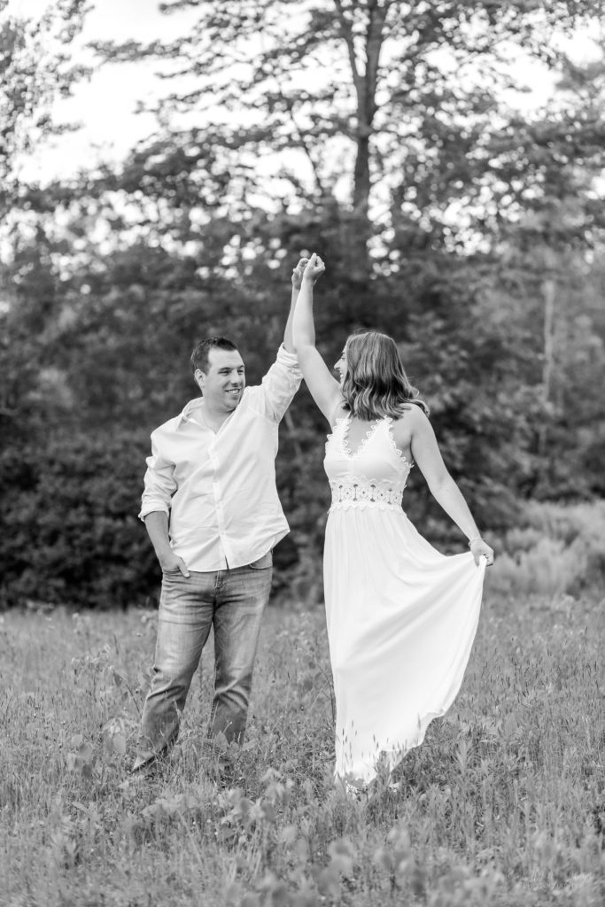 Black and white photo of man twirling woman in a field