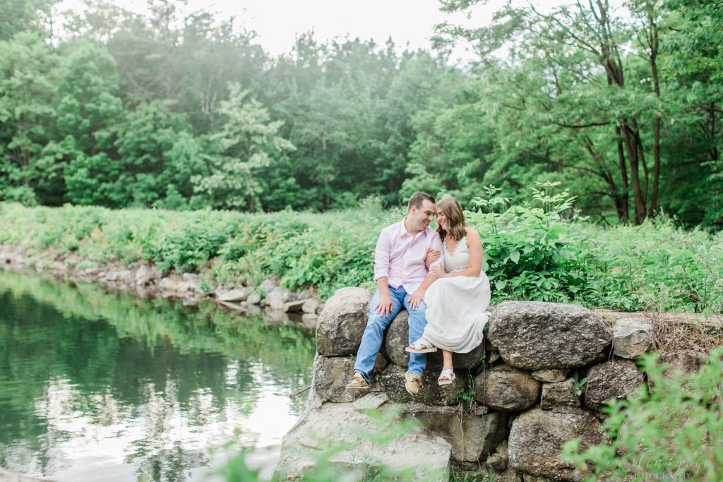 Man and woman sitting on a rock wall on the edge of a lake