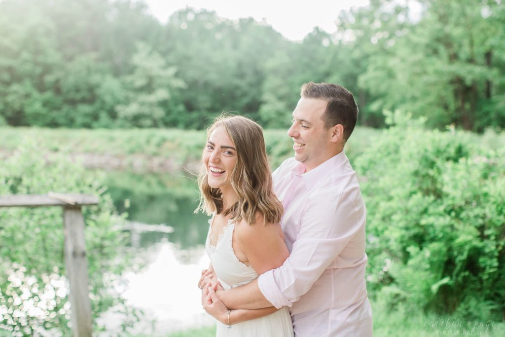 Man snuggling woman in front of lake