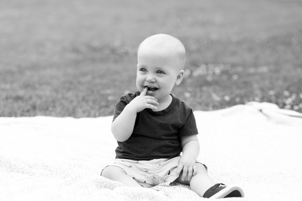 Black and white photo of toddler sitting n blanket on the grass