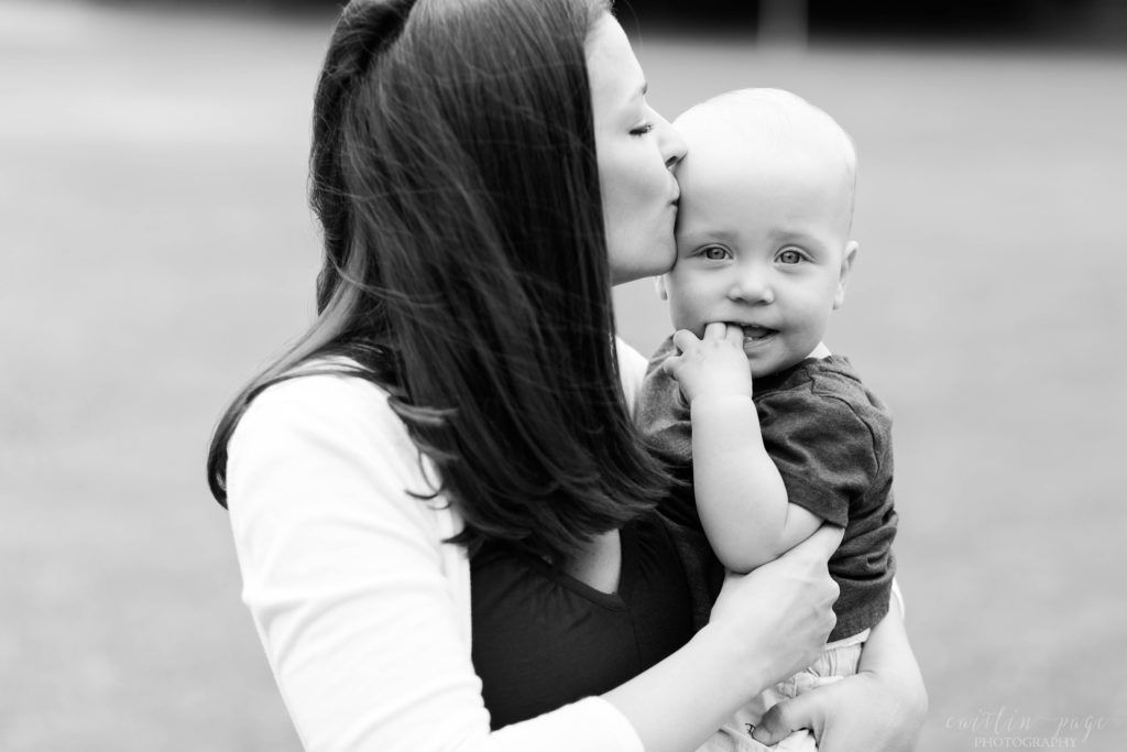 Black and white photo of mom kissing little boy on the cheek