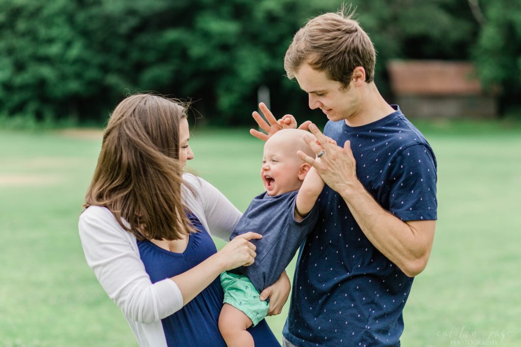 Toddler boy laughing as his parents hold him