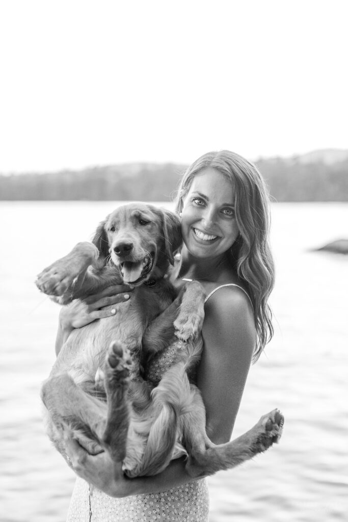 Woman holding golden retriever puppy in front of Squam Lake