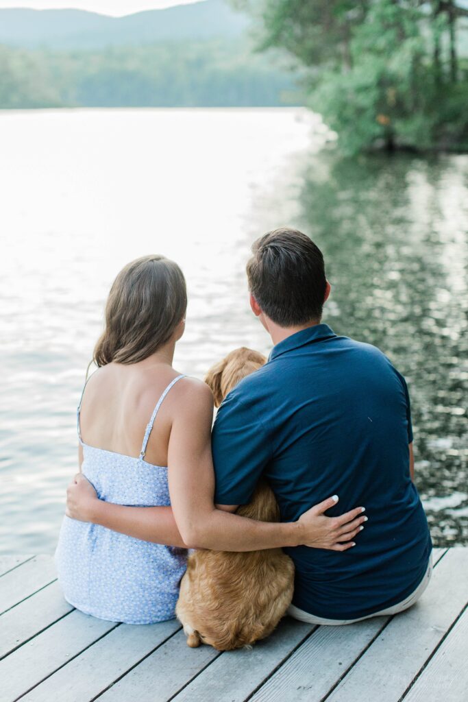 Man and woman sitting on dock with puppy on Squam Lake