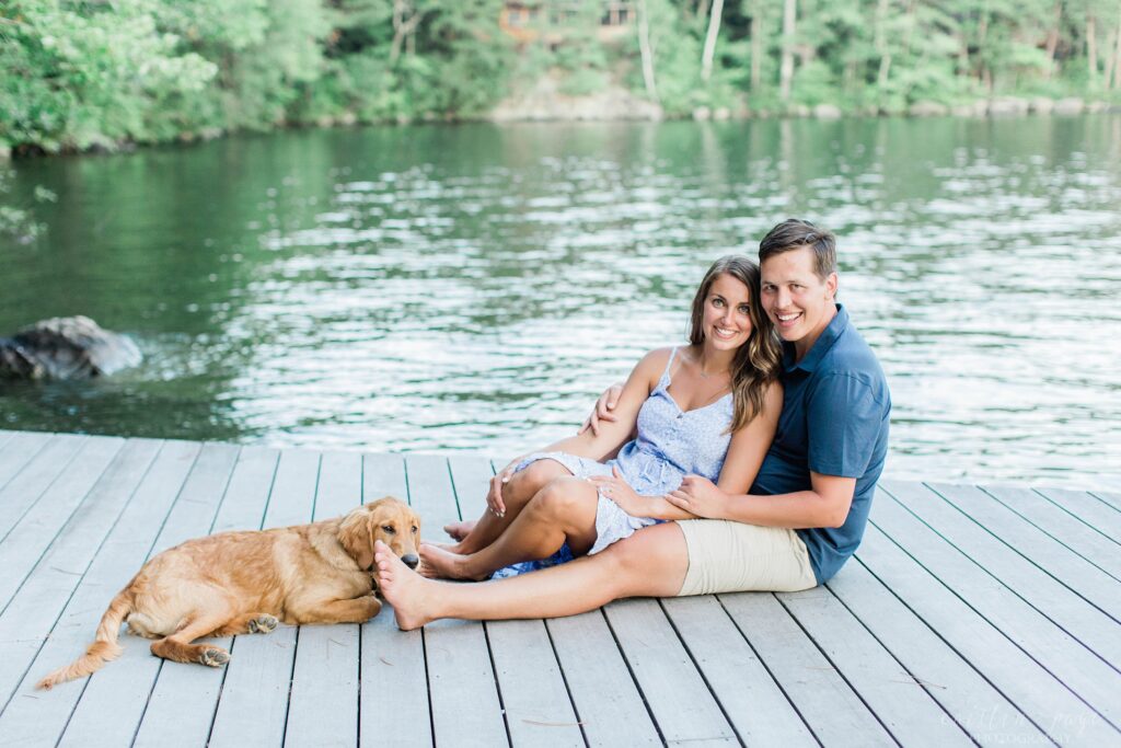 Man and woman sitting on dock with puppy