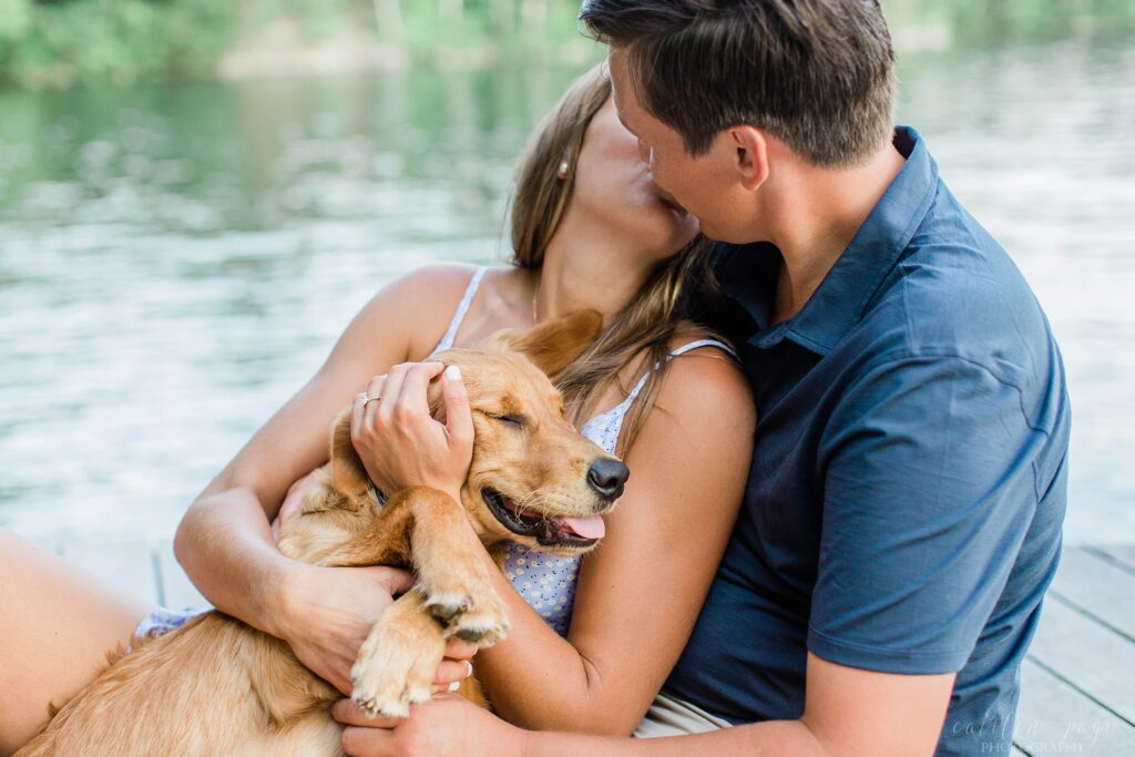 Man and woman snuggling with puppy on dock