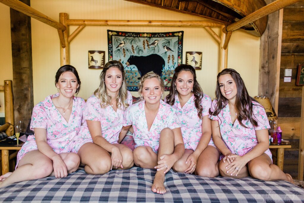 Bride and bridesmaids sitting together on bed with matching pajamas