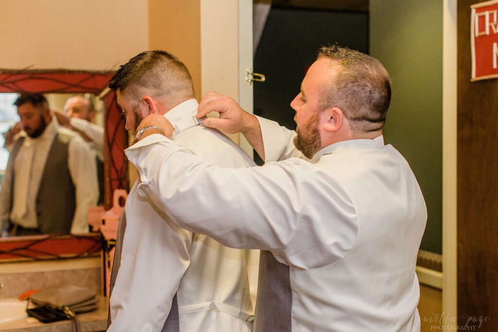 Groomsmen helping groom tie his tie