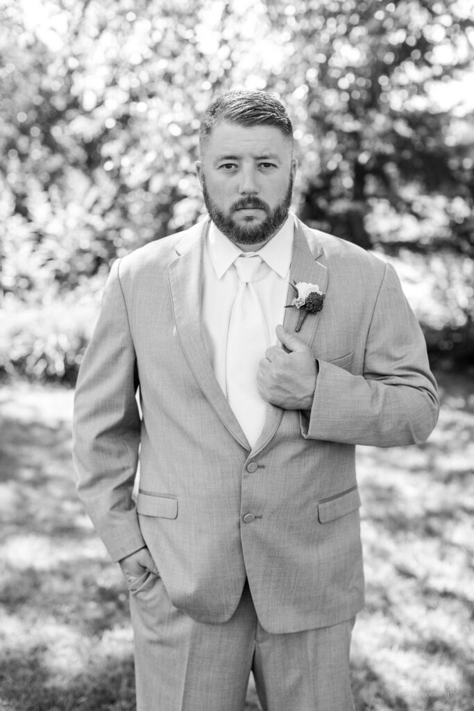 Black and white portrait of groom standing outside