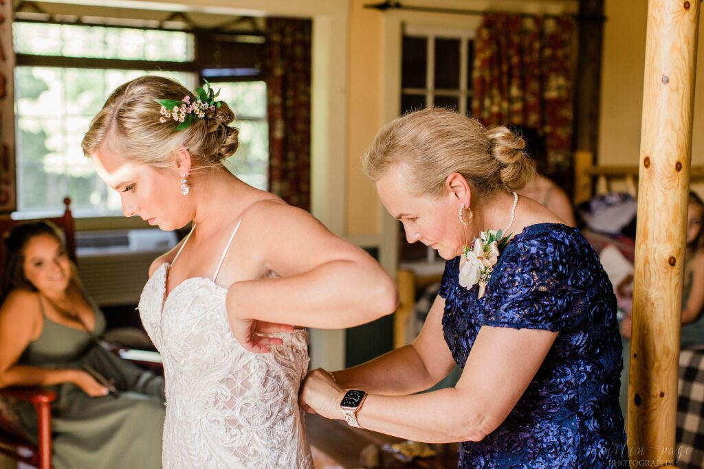 Mother of bride zipping up bride's dress