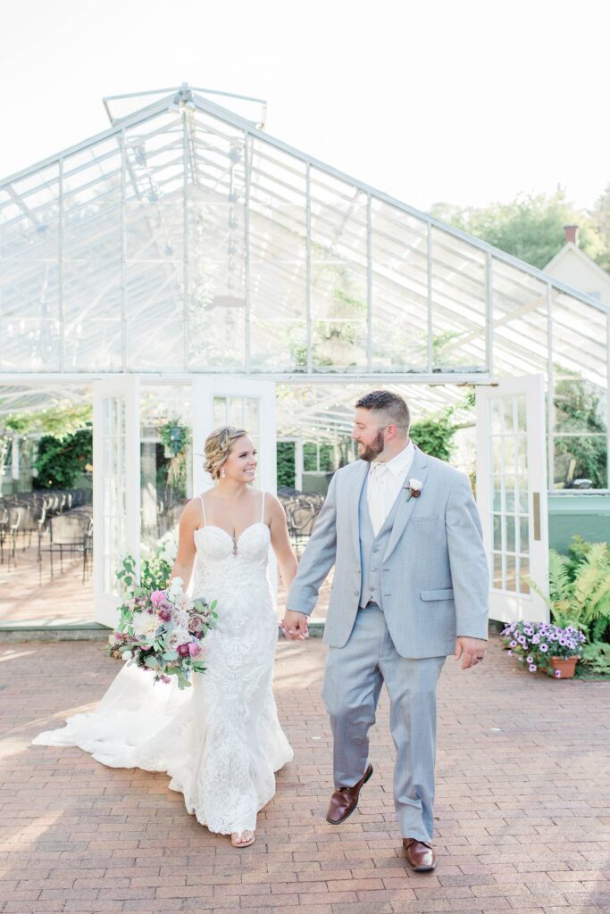 Bride and groom standing outside the greenhouse at the Barn on the Pemi
