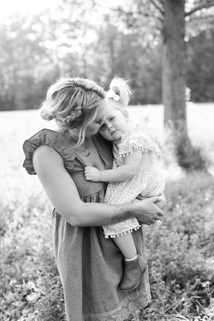 Black and white photo of little girl snuggling with her mom