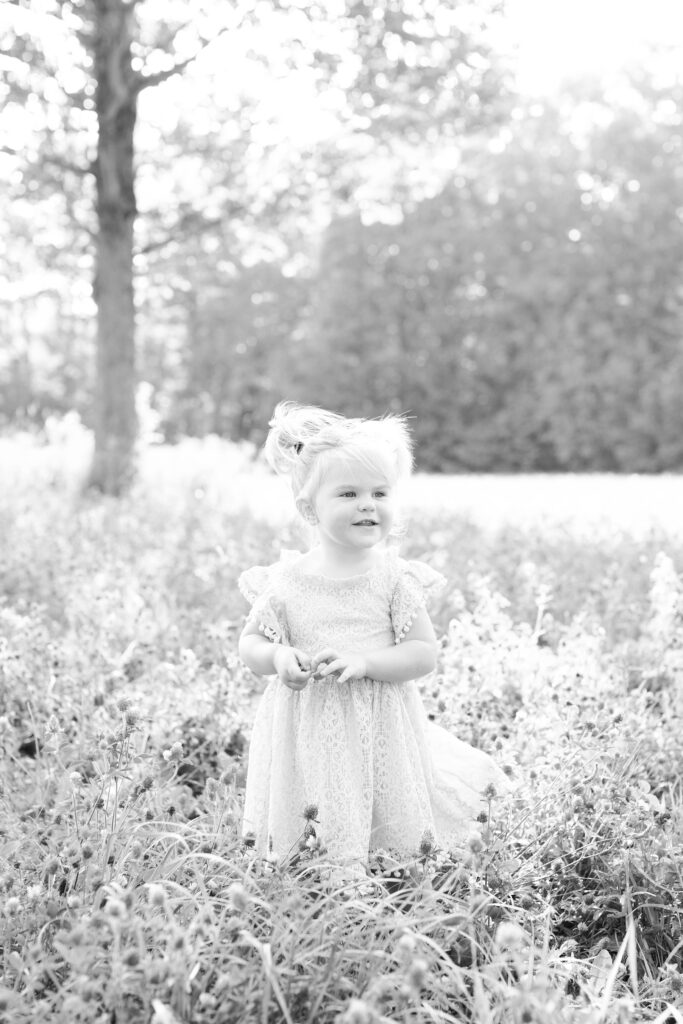 Black and white portrait of toddler girl in a field