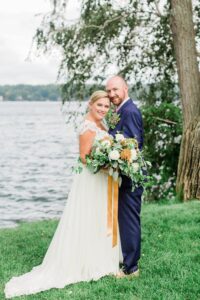 Portrait of bride and groom standing in front of Lake Winnipesaukee at Church Landing