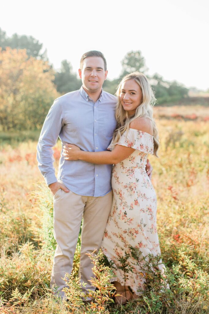 Couple standing together in field at sunset