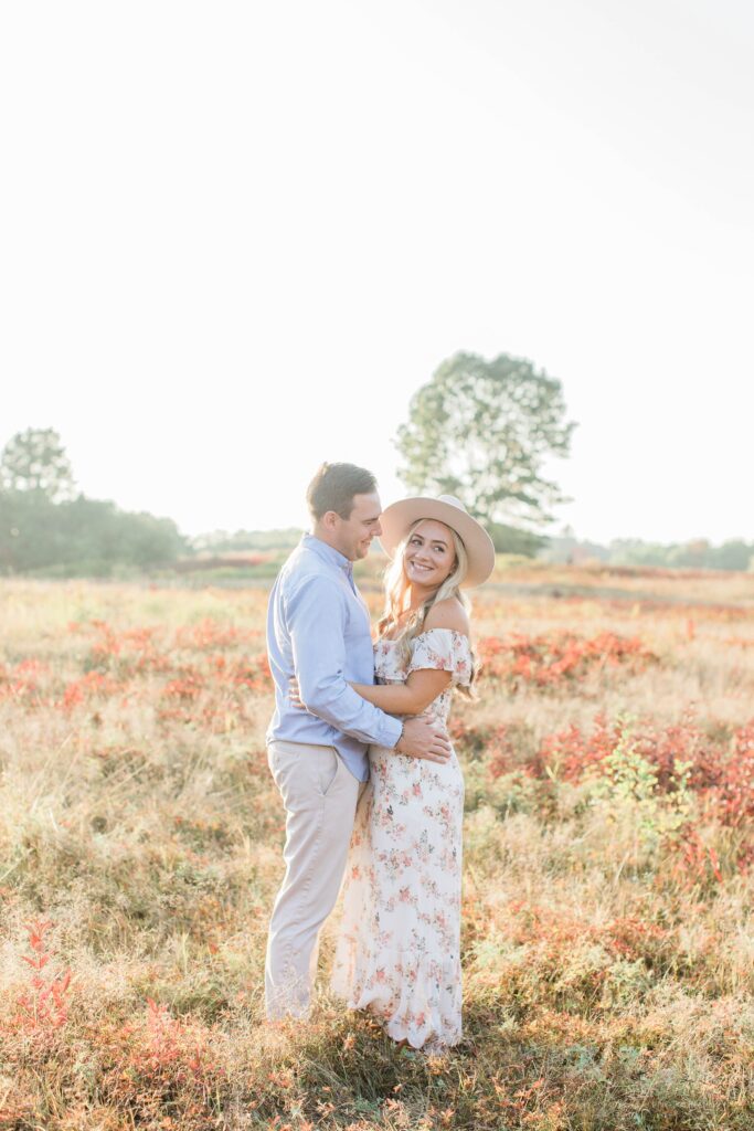 Man and woman standing together in field at sunset