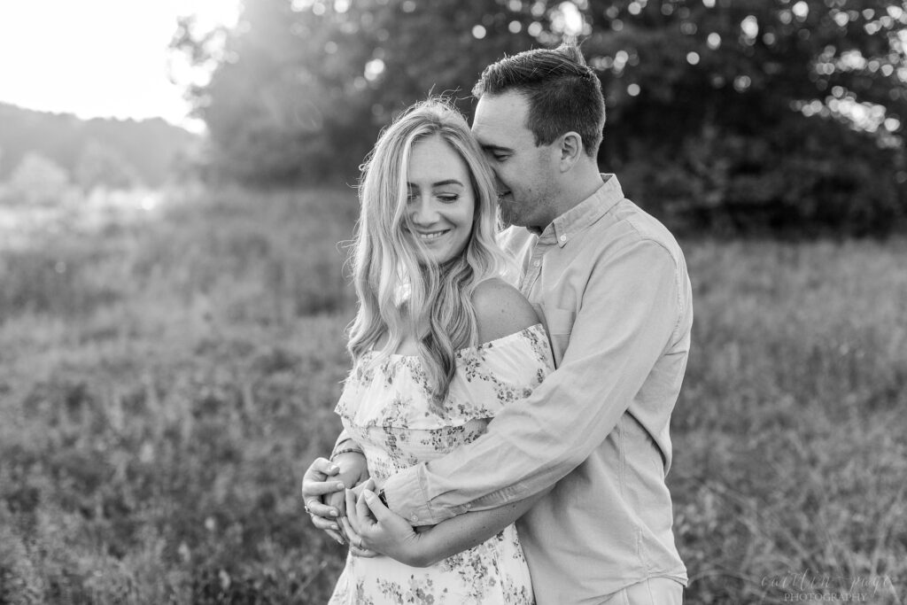 Black and white photo of man and woman snuggling in a field