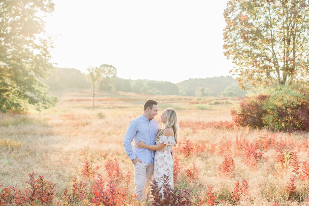 Man and woman standing together in field at sunset