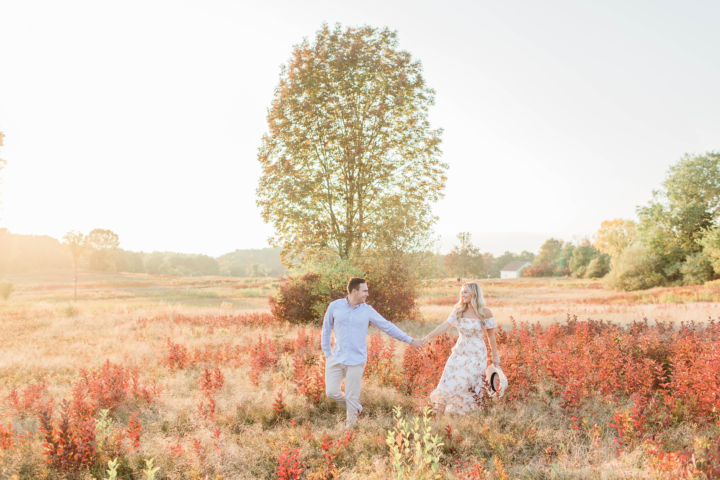 Man and woman walking through a field at sunset