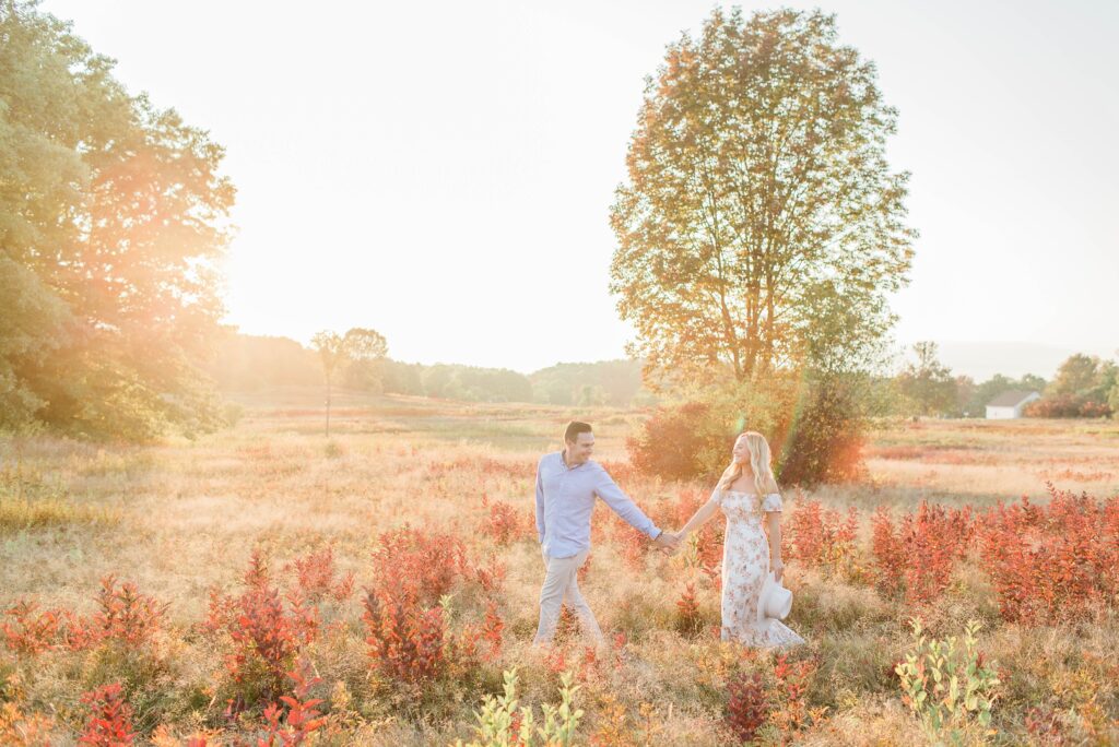 Man and woman walking through a field at sunset