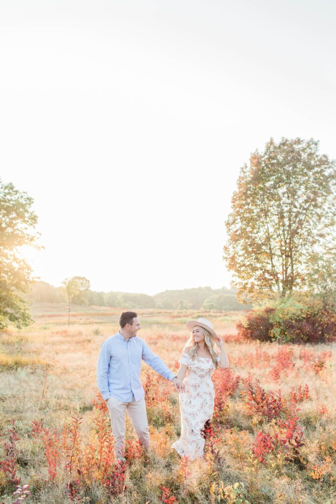 Man and woman walking through a field at sunset