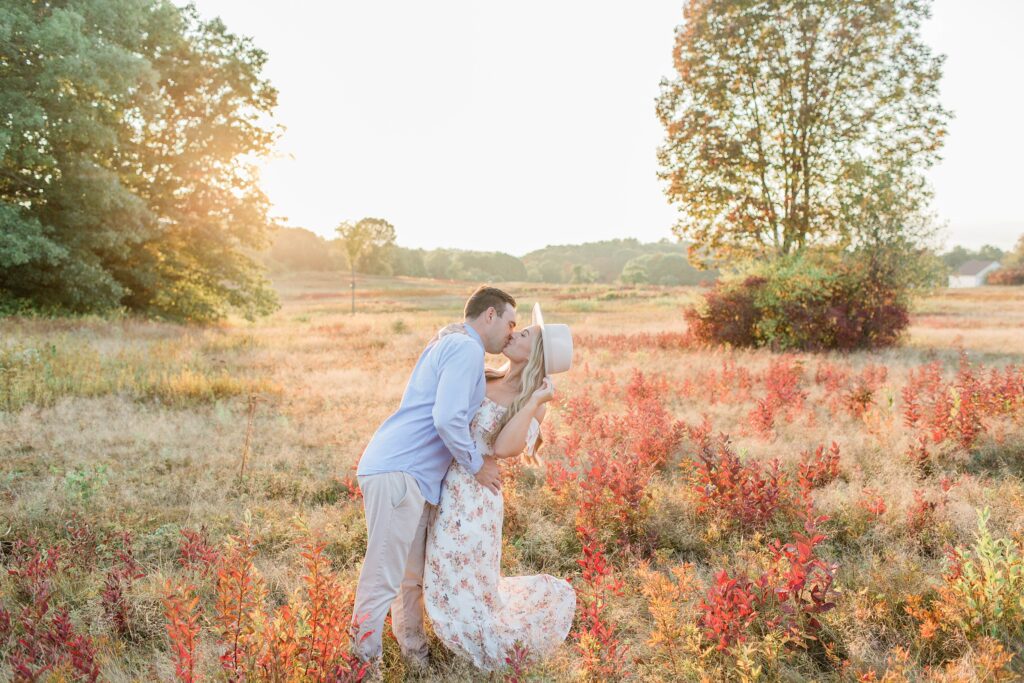 Man and woman kissing in a field at sunset