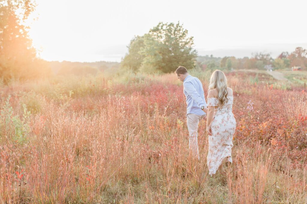 Man and woman walking through a field at sunset