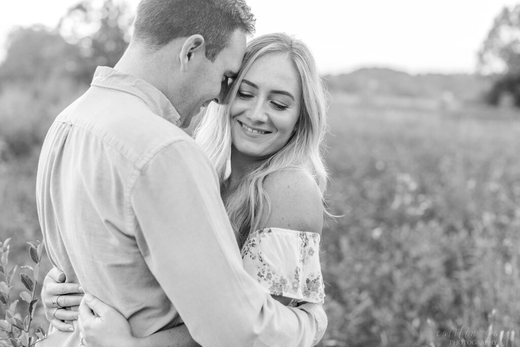 Black and white photo of man nuzzling woman in a field