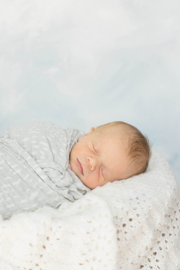Newborn baby boy in a gray swaddle