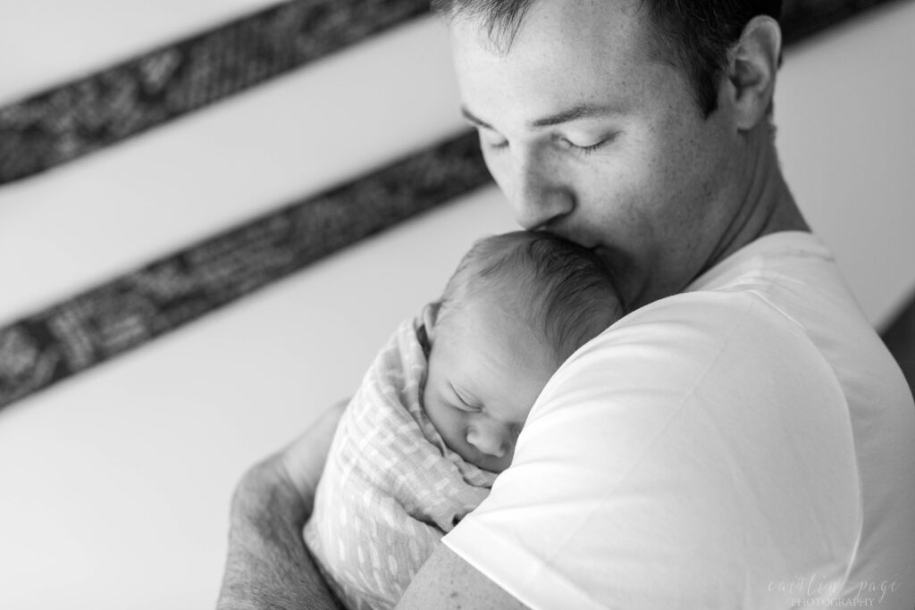 Black and white photo of dad holding newborn baby
