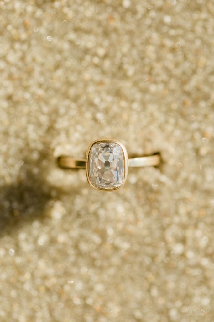 Solitaire engagement ring sitting in the sand
