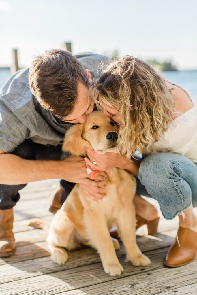 Man and woman giving golden retriever puppy kisses