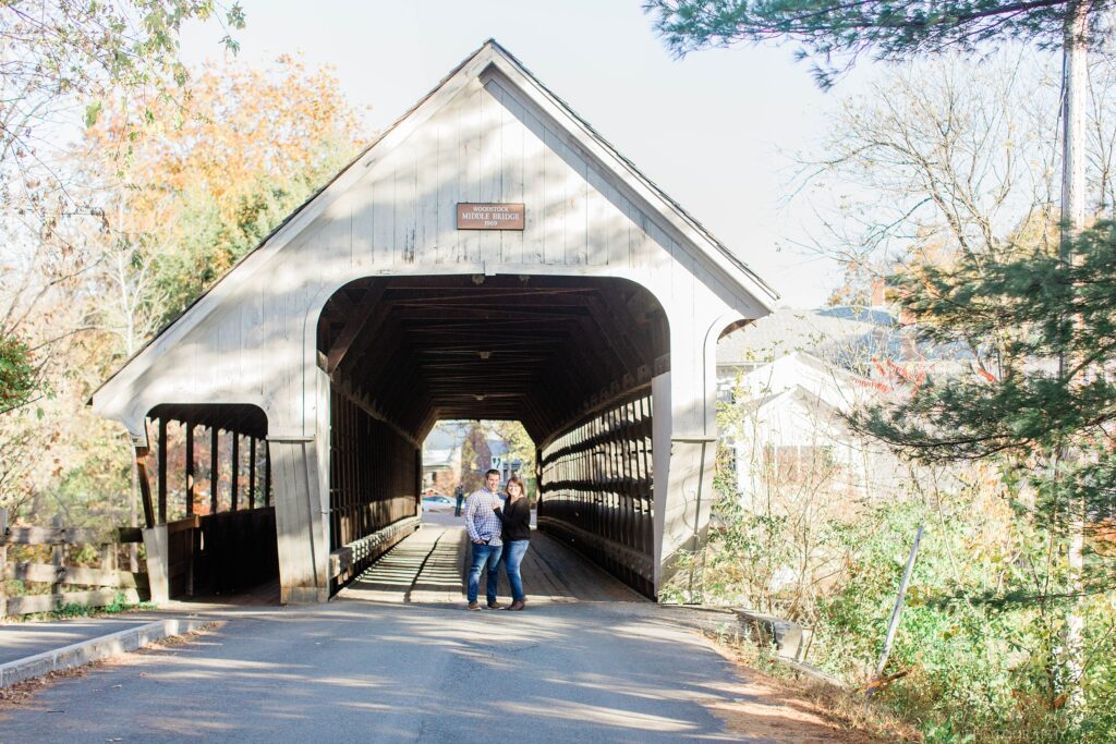 Couple standing together in front of covered bridge