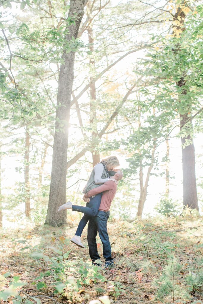 Man lifting woman in the air in the woods