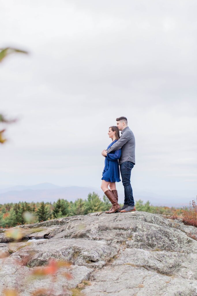 Couple standing on top of rock on mountaintop