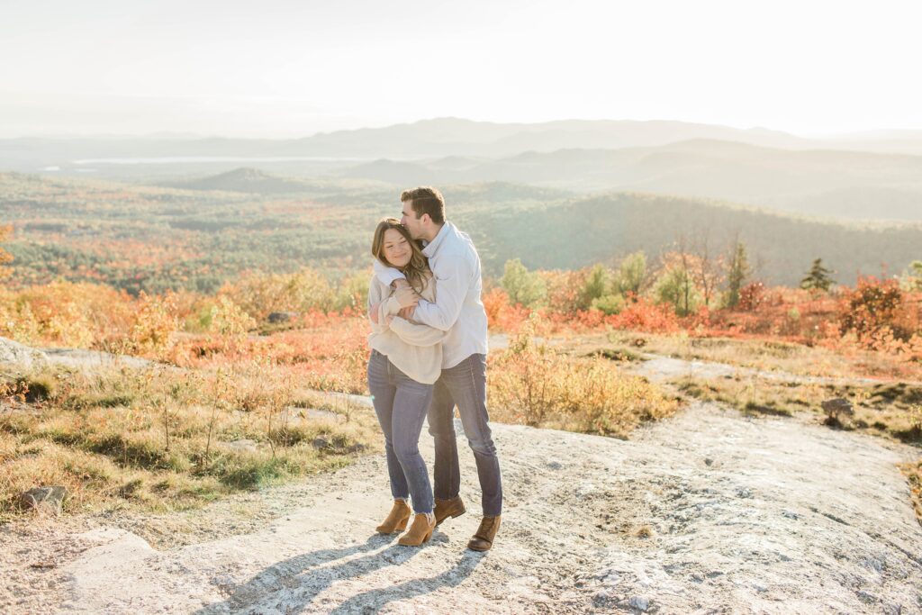 Man and woman standing together on top of mountain at sunset