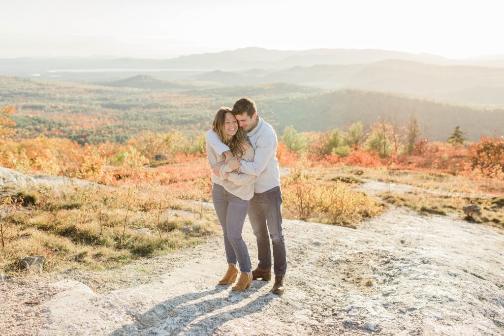 Man and woman standing together on top of mountain at sunset
