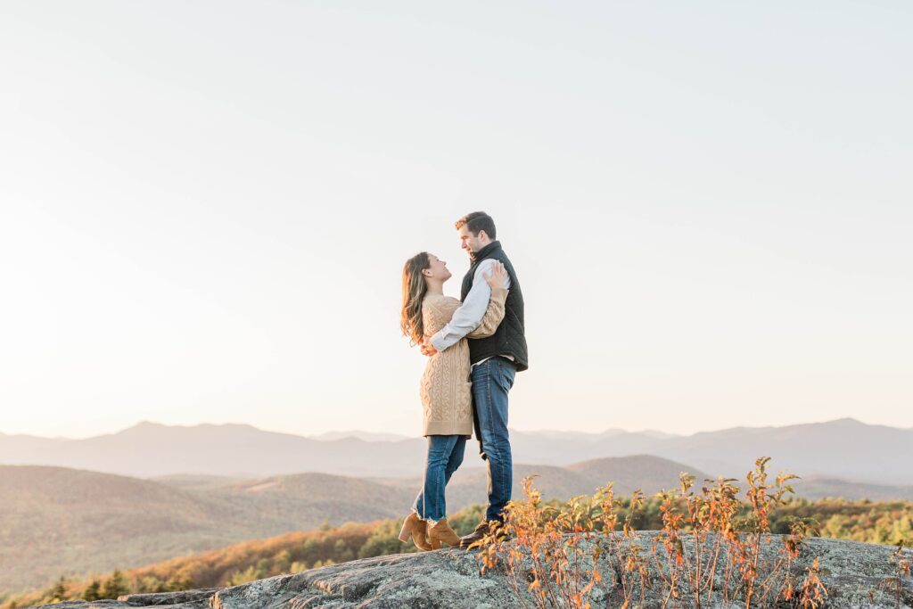 Man and woman snuggled together on top of mountain at sunset