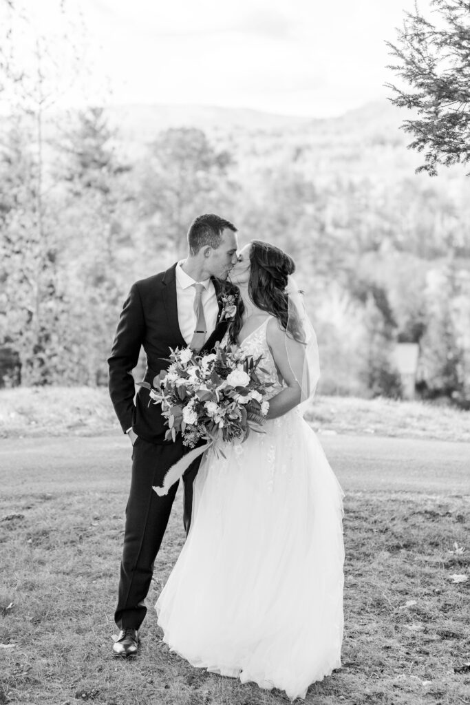 Black and white portrait of bride and groom standing together in front of mountains