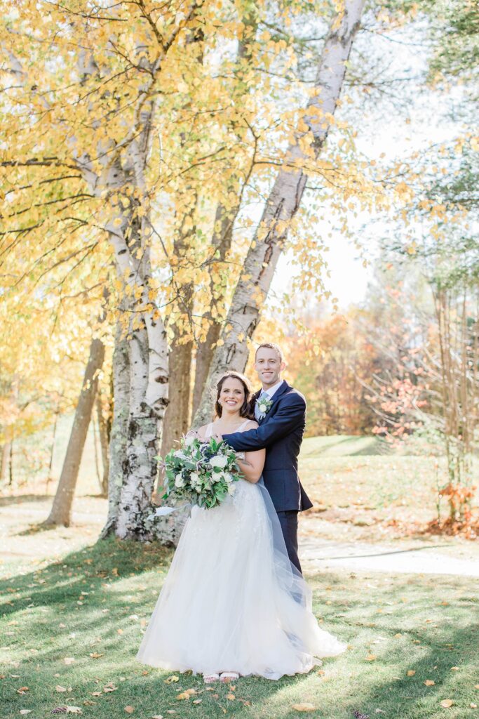 Bride and groom standing together in front of birch trees at Owl's Nest