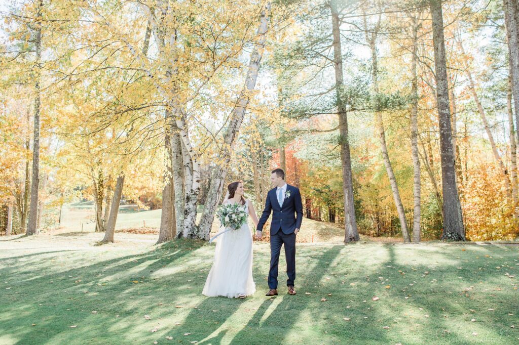 Bride and groom walking together in front of birch trees at Owl's Nest