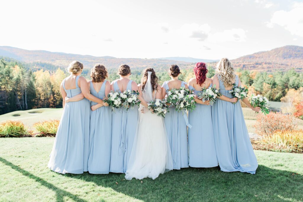 Bridesmaids standing together with arms linked behind their backs