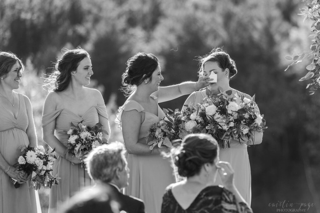 Bridesmaids wiping each others tears during wedding ceremony