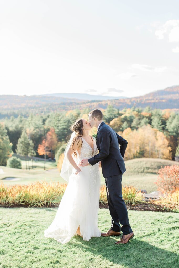 Groom kissing bride in front of mountains